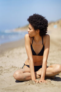 Young woman sitting on sand at beach