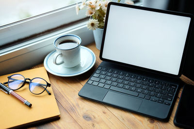 Coffee cup and laptop on table