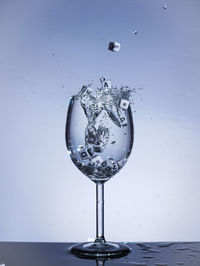 Close-up of water splashing on glass against white background