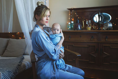 Portrait of cute girl sitting on bed at home