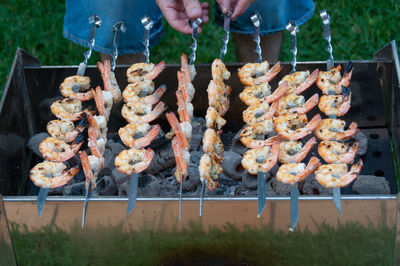 Close up of barbecue grill with prawns. outdoor picnic scene of person turning seafood bbq