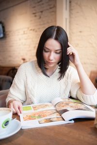 Woman looking at menu while sitting in restaurant