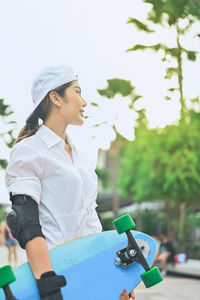 Woman holding skateboard while standing outdoors