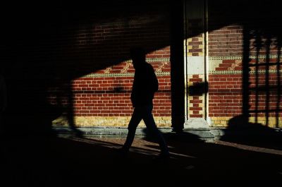 Silhouette man walking by wall