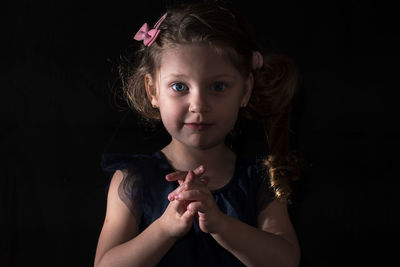 Portrait of cute girl against black background
