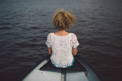 Rear view of woman sitting on boat in lake