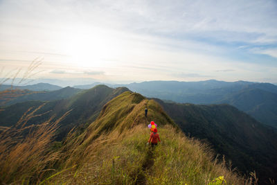 Rear view of man standing on mountain against sky