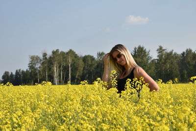 Woman standing amidst yellow flowering plants