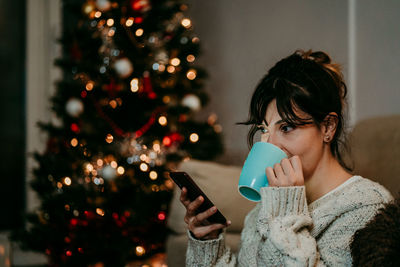 Young woman holding christmas tree at home