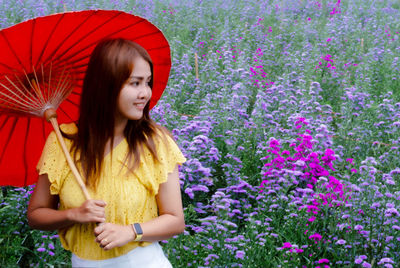 Beautiful woman standing by purple flowering plants on field