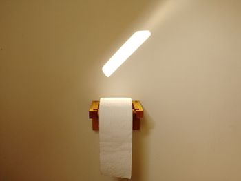 Low angle view of illuminated lamp against wall at home