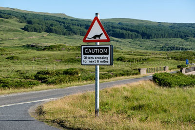 Road signs on landscape against sky.