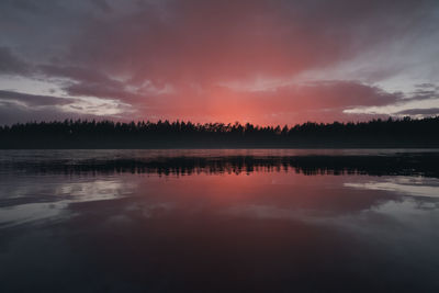 A cloud illuminated by the setting sun over a picturesque forest lake