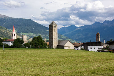 Scenic view of field by buildings against sky