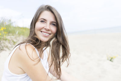 Portrait of beautiful woman at beach against sky