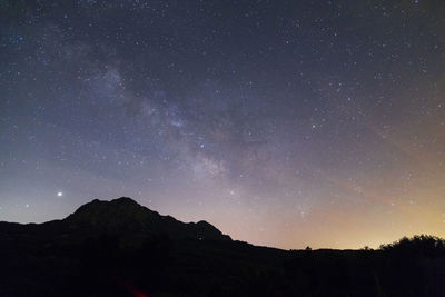 Low angle view of silhouette landscape against star field at night