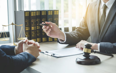 Man holding mobile phone while sitting on table