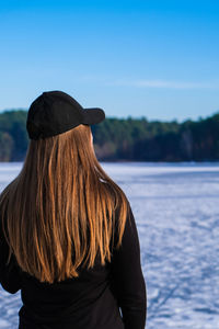 Young female woman back to the camera with long hair in a snow landscape. happy hipster 