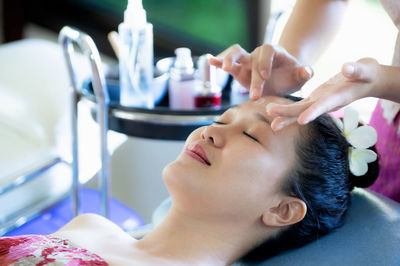 Woman lays down to the staff to clean her skin and apply moisturizer, skin care around her face.