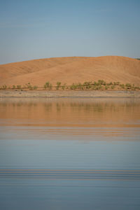 Desert like hill landscape with reflection on the water on a dam lake reservoir in terena, portugal