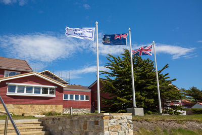 Low angle view of flag by building against sky