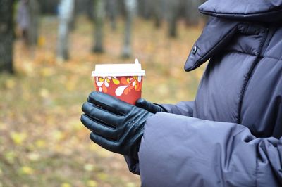 Midsection of man holding coffee at park