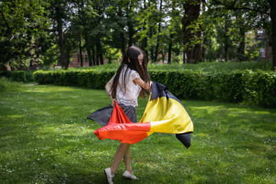 Portrait of a girl with a belgian flag in the park.