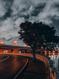 Illuminated bridge by river against sky at night