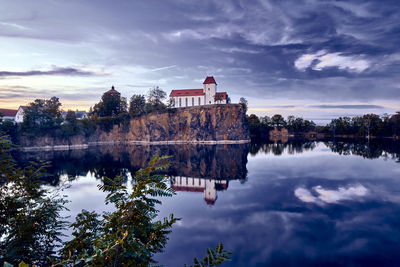 Reflection of building in lake against sky at sunset