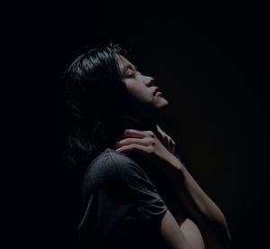 Portrait of woman looking away against black background