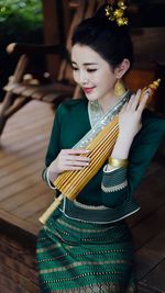 Portrait of smiling young woman standing against wall