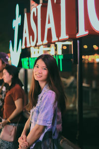 Portrait of a smiling girl standing on illuminated text