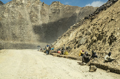 People working on mountain against sky