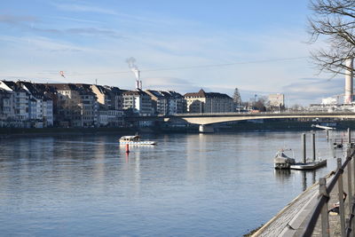 Sailboats on bridge over river against sky in city