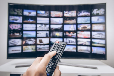 Cropped hand of man holding remote control at home