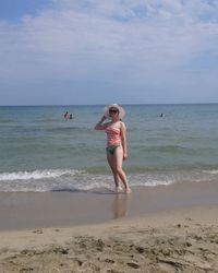 Woman standing on shore at beach against sky