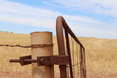 Close-up of rusty metal on field against sky