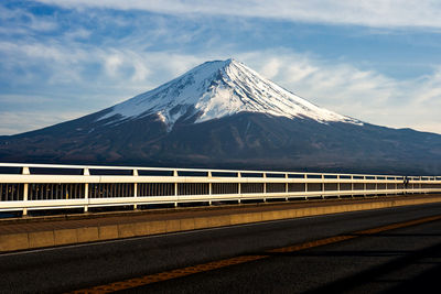 Road leading towards snowcapped mountains against sky