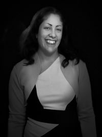 Portrait of smiling woman standing against black background