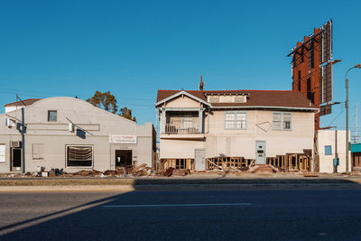 Road by buildings against blue sky