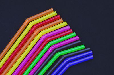 Directly above shot of multi colored drinking straws against black background