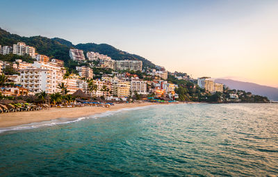 Buildings by sea against sky