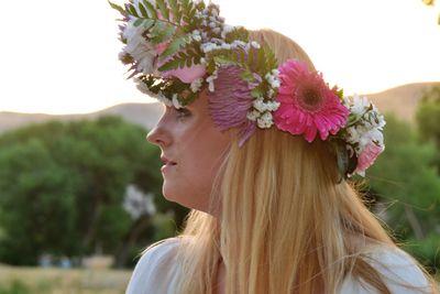 Close-up of young woman with flowers against blurred background