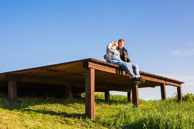 People sitting on wood against clear sky