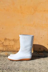 Close-up of white rubber boots against wall