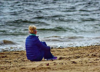 Rear view of woman sitting on beach