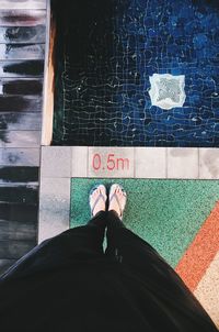 Low section of man standing by swimming pool