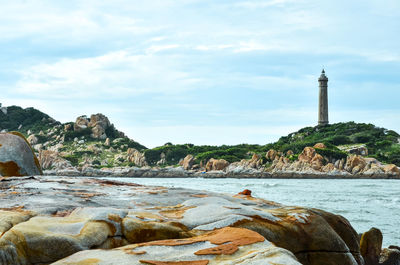 Rock formations in water against cloudy sky