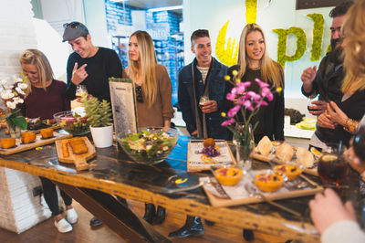 Happy friends standing by food at table in restaurant