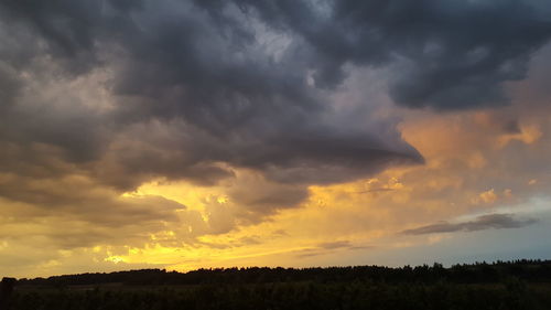 Scenic view of dramatic sky over field during sunset